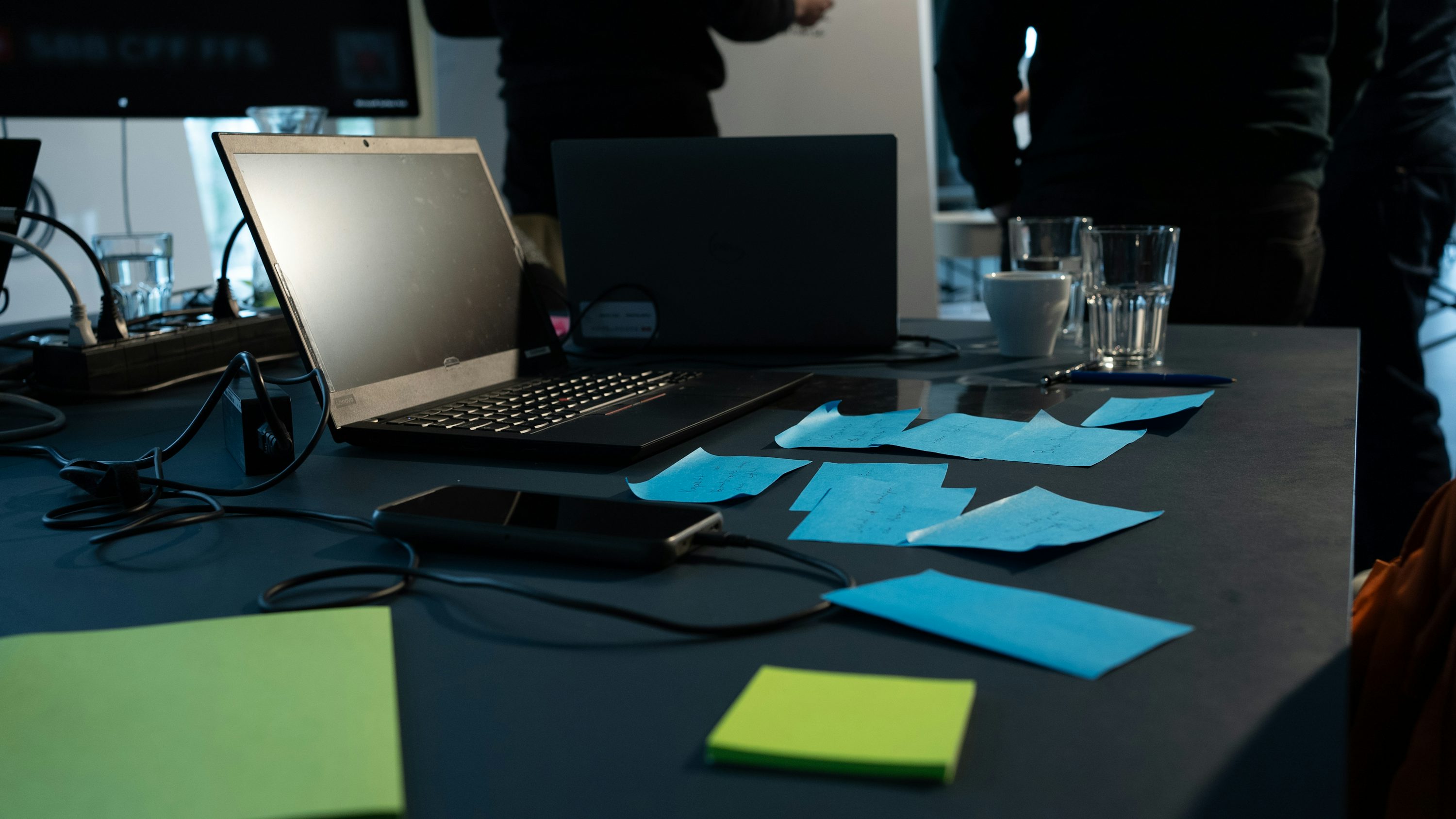 Post-its et ordinateurs sur une table de travail pour illustrer l’ordre entre branding et marketing.